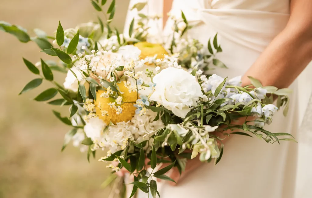 Bouquet de fleurs naturel et déstructuré style Dolce Vita avec fleurs jaunes, blanches et bleu clair – Poppy & Daisy