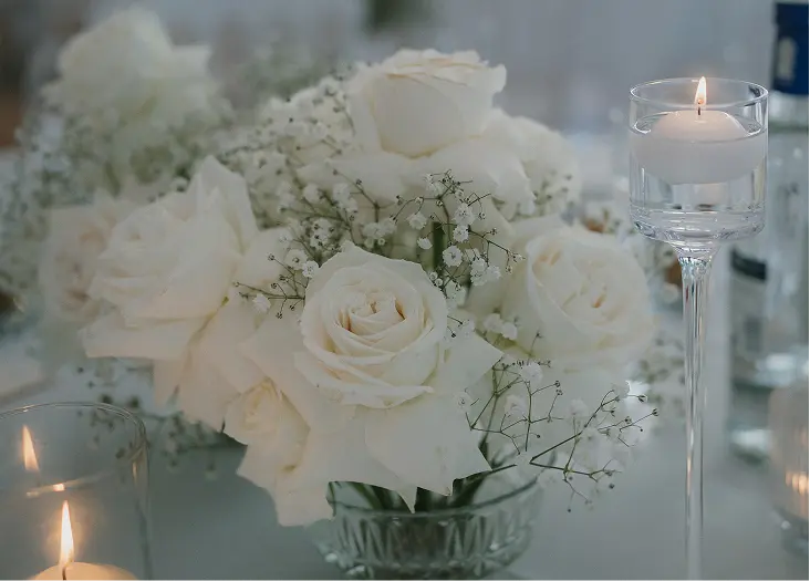 Composition de roses blanches et gypsophile avec bougies flottantes