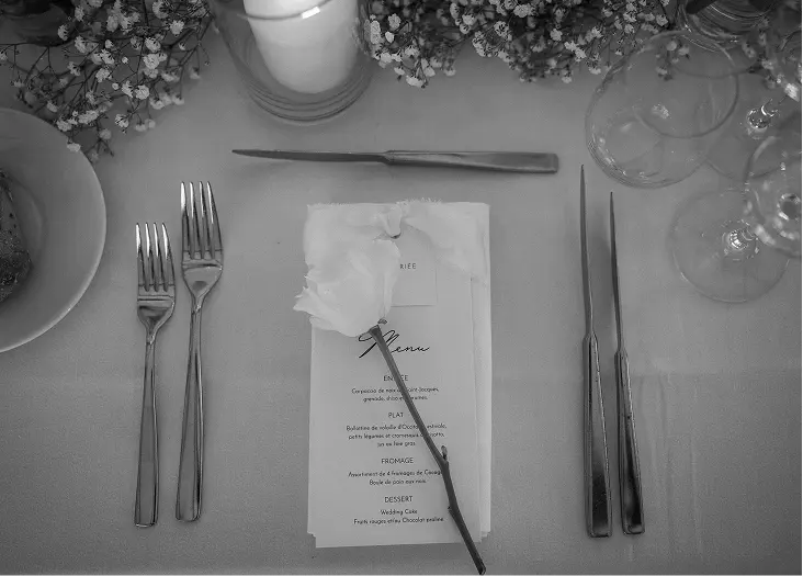 Rose blanche posée sur le menu d’une table de réception
