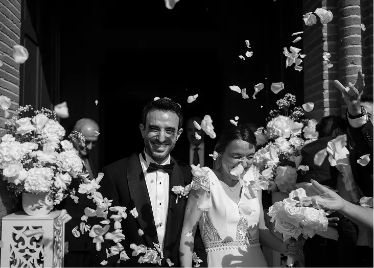 Sortie des mariés sous une pluie de pétales de roses blanches
