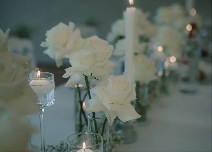 Tables de réception luxueuses avec roses blanches, bougies et gypsophile