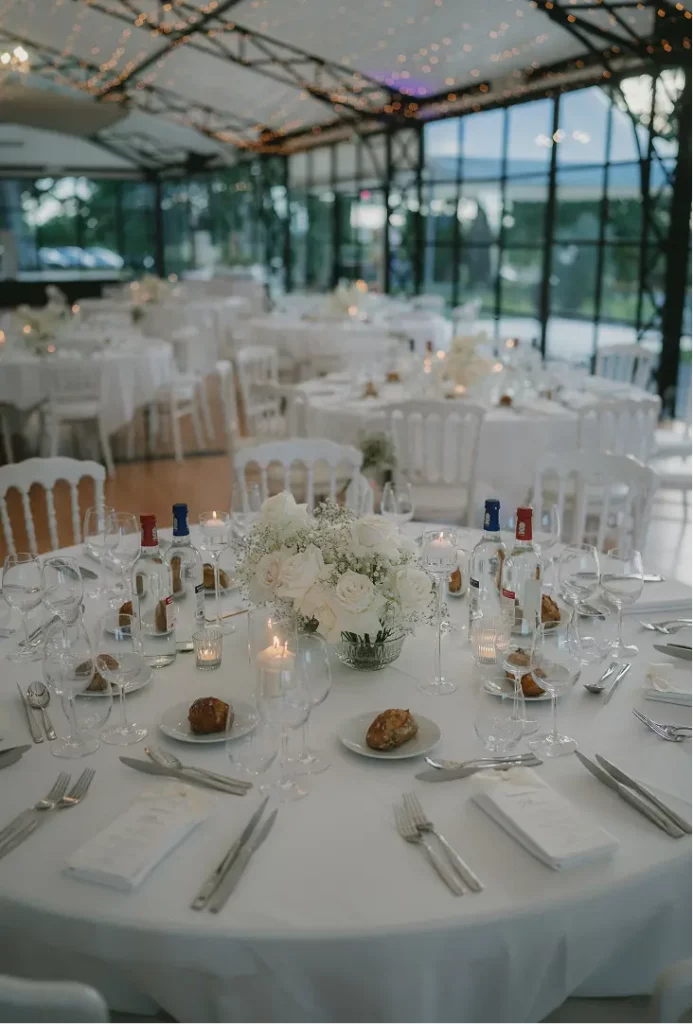 Tables rondes de mariage avec nappes blanches et compositions florales blanches